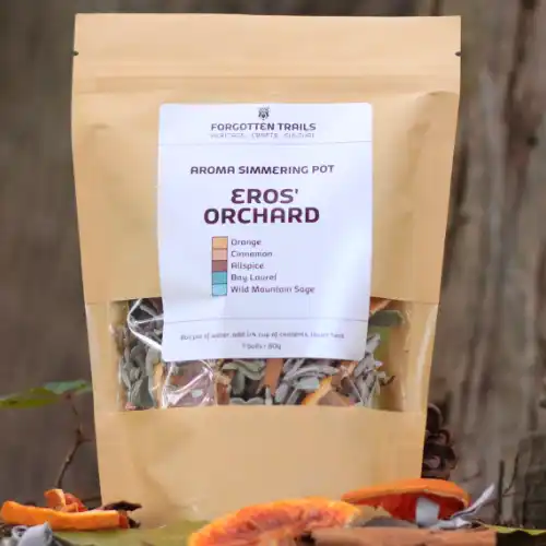 A kraft paper pouch of Eros' Orchard aroma simmering pot with dried orange, cinnamon, allspice, bay laurel, and sage, outdoors.